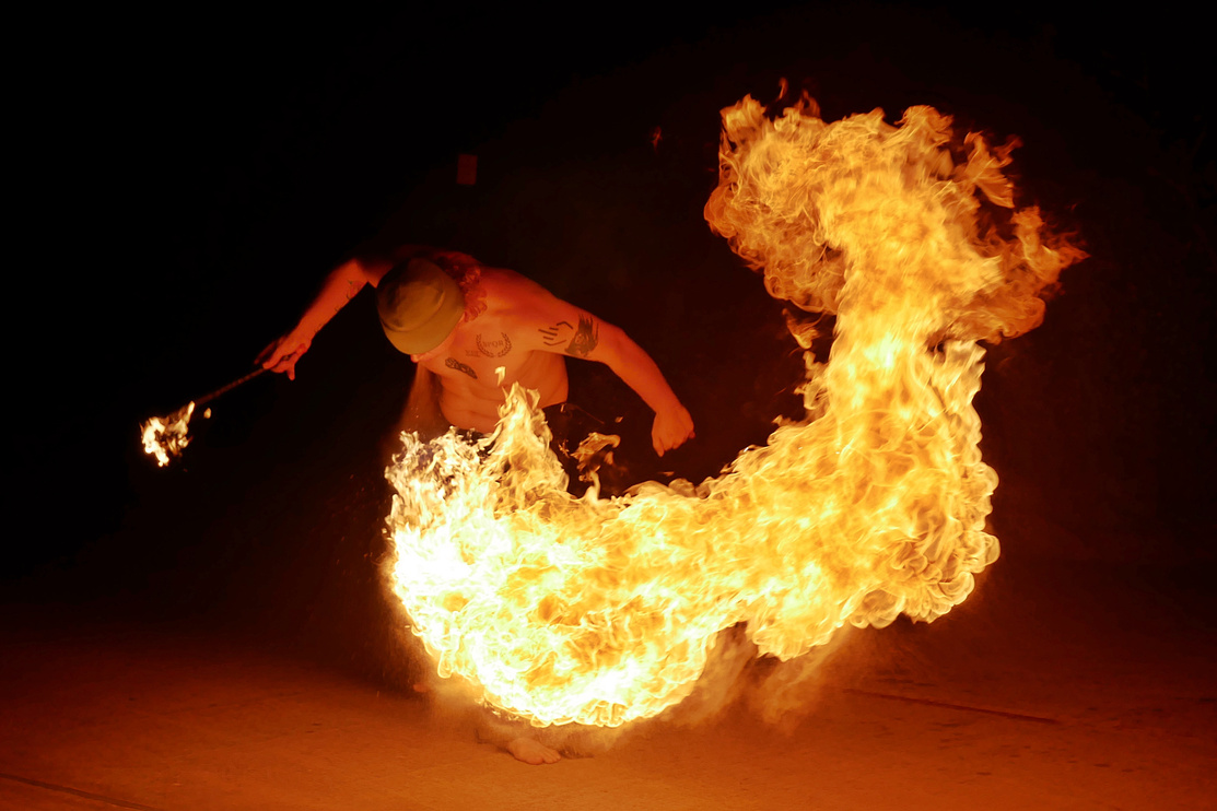 A photo I took of a fire-breather performing a move where they create a giant swirl of fire. The only light illuminating the performer is the flame.